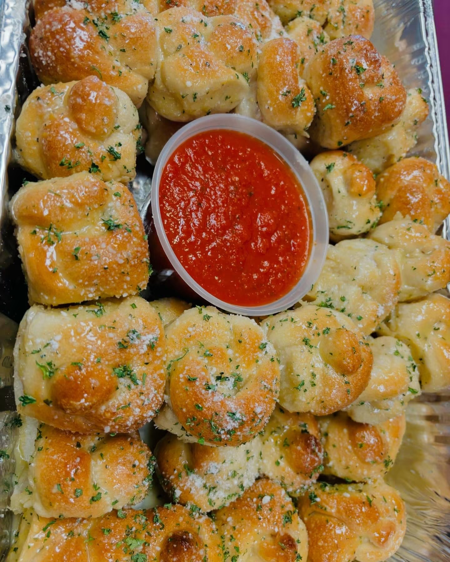 Tray of garlic knots with marinara sauce